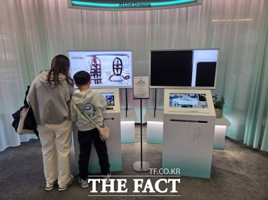 지난 22일 서울 광화문 KT사옥 'KT 온마루' 전시관을 찾은 한 모자 방문객이 대한민국 통신 역사를 체험한 뒤 전시관 내에 설치된 'AI 라이브 드로잉'을 체험하고 있다. /종로=우지수 기자