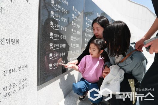 희생자 가족들이 고인의 이름이 새겨진 명판을 쓰다듬고 있다.