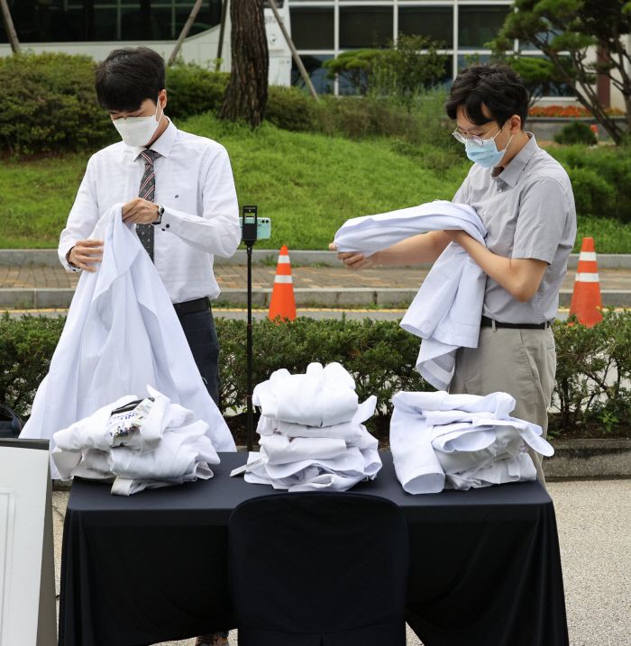 23일 오전 서울 종로구 서울대병원 대학의원 본관 앞에서 정부의 의료정책에 반대하는 전공의들이 의사 가운을 탈의하고 있다. 연합뉴스
