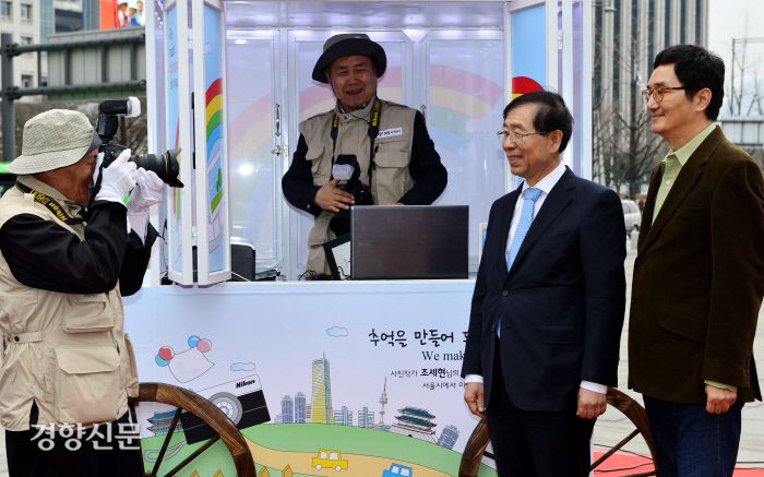 홈리스 사진사 하성수(사진왼쪽)와 최범석씨가 2013년 3월 28일 서울 광화문 광장에서 희망사진관 1호점 개소식을 마친 후 박원순 전 서울시장과 사진작가 조세현씨를 첫손님으로 찍고 있다./ 정지윤 기자