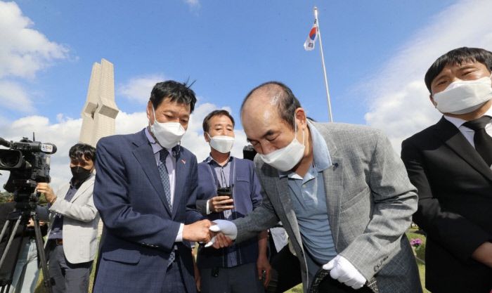 광주 북구 국립5·18민주묘지에서 21일 오후 신순용 전 육군 소령(오른쪽 두번째)이 사죄의 뜻을 나타내자 김영훈 5·18 유족회장(왼쪽 두 번째)이 그의 손을 잡아 주고 있다. 연합뉴스