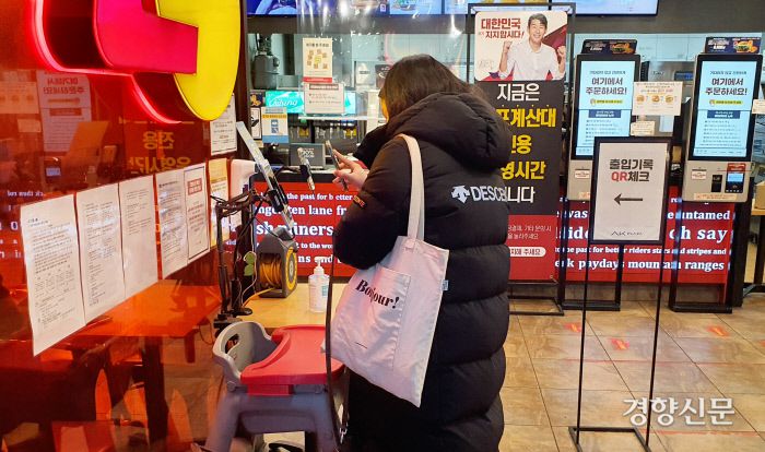 QR체크인을 시도하는 한혜경 디지털시각장애연대 대표 뒤로 ‘지금은 셀프계산대 전용 운영시간입니다’라고 쓰인 입간판과 키오스크 기계들이 보인다. 이유진 기자