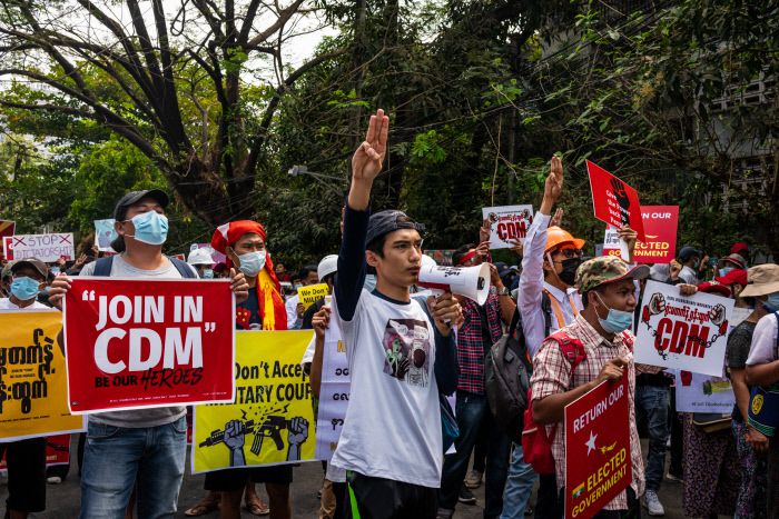 지난해 2월15일(현지시간) 미얀마 양곤에서 시민들이 중앙은행 건물 앞에서 ‘우리는 정의를 원한다’는 표시로 세 손가락 경례를 하며 현수막을 들고 구호를 외치고 있다. |  게티이미지
