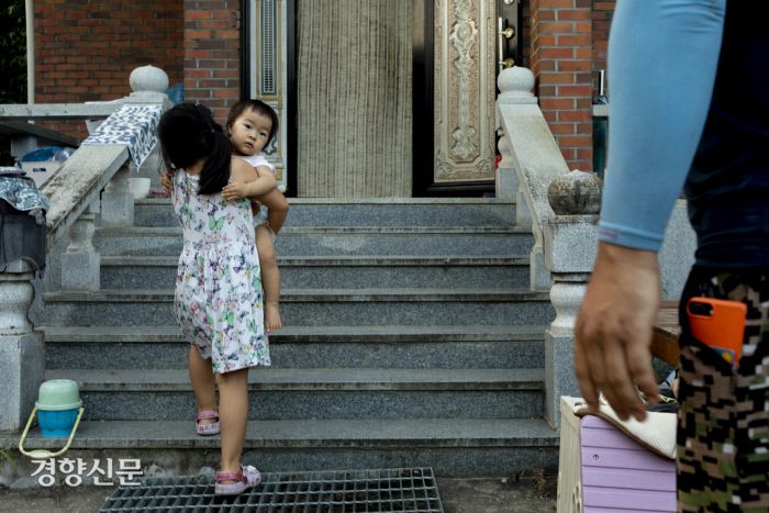 둘째 연희가 막내 연재를 안고 집으로 들어가고 있다.