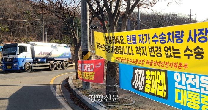 지난 8일 경기 판교저유소 앞에 걸려 있는 화물연대 현수막 앞을 탱크로리 차량이 지나고 있다. 김태희기자