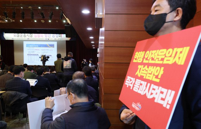 ‘화물운송 정상화 공청회’ 연 국토부 서울 중구 포스트타워에서 18일 국토교통부가 주최한 화물운송시장 정상화 방안 공청회에서 화물연대 노조원들이 요구사항을 적은 팻말을 들고 있다. 연합뉴스