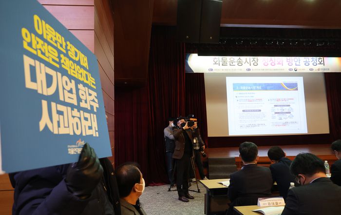 18일 서울 중구 포스트타워에서 국토부가 주최한 화물운송시장 정상화 방안 공청회에서 화물연대 노조원들이 요구사항 팻말을 들고 있다.  연합뉴스