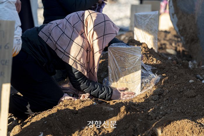 튀르키예·시리아 대지진 8일째인 13일(현지시간) 튀르키예 남부 카라만마라슈의 남쪽 교외의 한 공터에 마련된 지진 희생자 매장지에서 한 유족이 나무 묘비에 비닐을 씌우고 있다. 카라만마라슈(튀르키예)｜문재원 기자