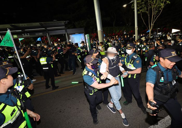 금속노조 조합원과 비정규직 노동단체 회원들이 25일 오후 서울 서초구 대법원 앞에서 열린 야간 문화제에서 이를 봉쇄하던 경찰과 대치 중 연행되고 있다. 연합뉴스