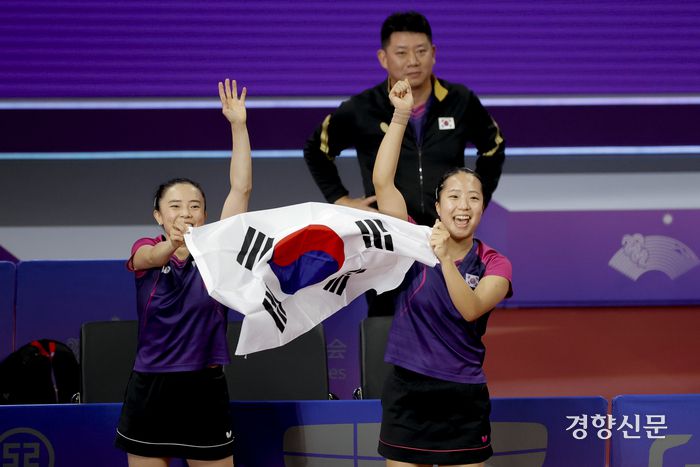 전지희(왼쪽)와 신유빈이 지난 2일 중국 항저우 중국 항저우 궁슈 캐널 스포츠파크 체육관에서 열린 탁구 여자 복식 결승전에서 금메달을 획득한 뒤 태극기를 들고 기뻐하고 있다. 뒤는 오광헌 여자 탁구대표팀 감독이다. 항저우 l 문재원 기자
