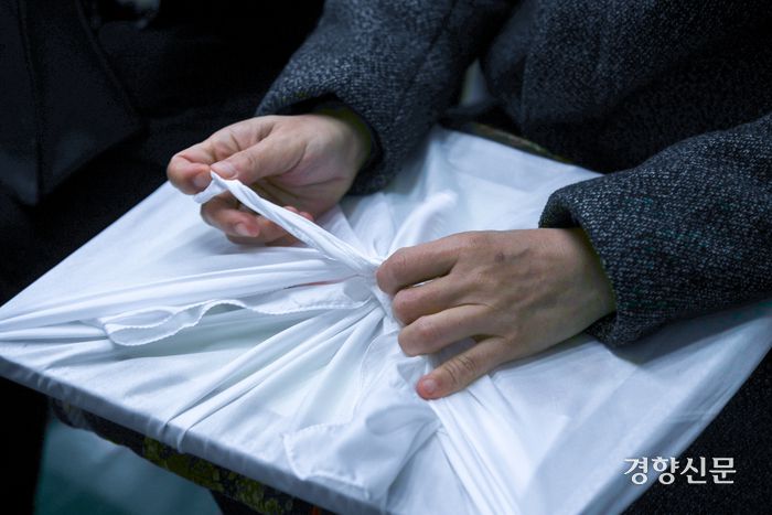 이태원 참사 희생자 고 진세은씨의 아버지 진정호씨가 15일 딸의 모교인 서울 구로구 성공회대학교에서 열린 학위수여식에 참석해 영정이 담긴 보자기를 풀고 있다. 성동훈 기자