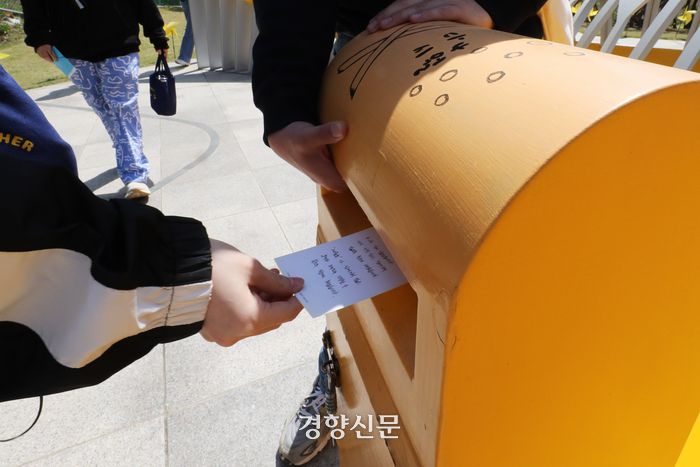 경기 안산시 고잔동 주민이 세월호 참사 이후 변화된 마을 이야기를 들려주는 ‘고잔동 마을 걷기’ 프로그램에 참가한 시민이 지난 14일 단원고등학교에서 세월호 참사 유가족에게 보내는 엽서를 우체통에 넣고 있다. 한수빈 기자