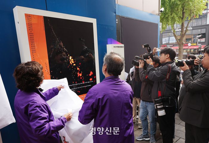 서울 용산구 이태원역 1번 출구 인근 사고 현장에서 28일 열린 10·29 이태원 참사 2주기 ‘기억과 안전의 길’ 빌보드 개막 기자회견에서 유가족들이 작품에 덮힌 천을 걷고 있다. 사진공동취재단