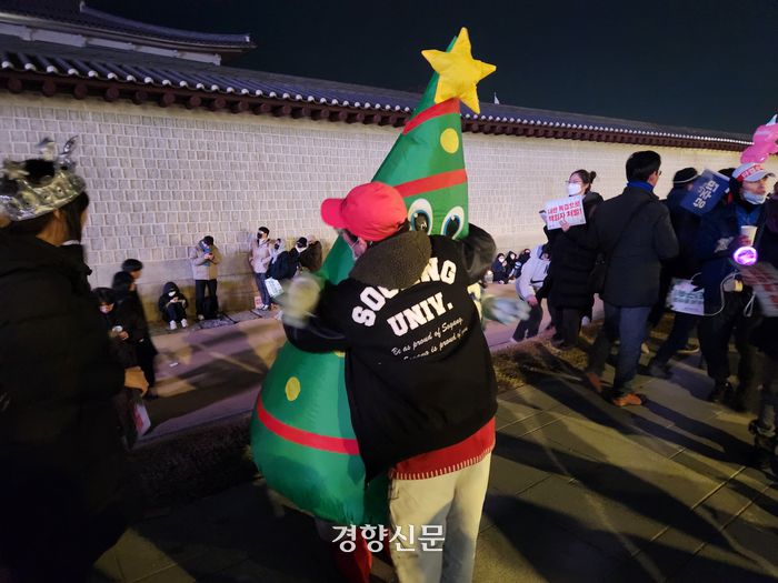 크리스마스 트리 코스튬을 입은 A씨(30)가 24일 서울 종로구 경복궁역 앞에서 시민을 안아주고 있다. 배시은 기자