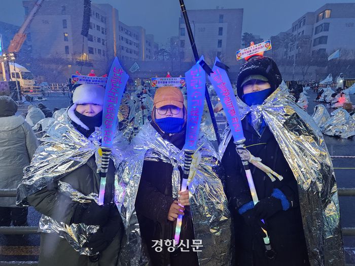 5일 서울 용산구 한남동 대통령 관저 인근에서 포항에서 온 장현옥씨(45·가운데)와 동네 지인들이 ‘반란수괴 윤석열 체포’라고 적힌 장난감 언월도를 들고 있다.  오동욱 기자