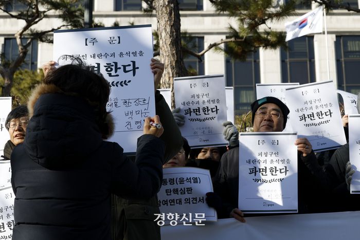 참여연대가 17일 서울 종로구 헌법재판소 앞에서 열린 ‘헌법파괴 내란수괴 윤석열을 파면하라’ 기자회견 중 ‘시민재판관’란에 자신의 이름을 적어내는 퍼포먼스를 하고 있다. 문재원 기자