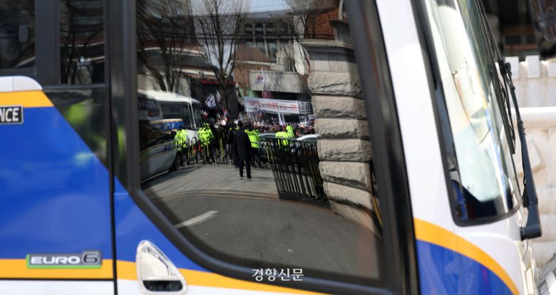 헌법재판소에 세워진 경찰 버스에 윤 대통령 지지자들의 모습이 비춰지고 있다.