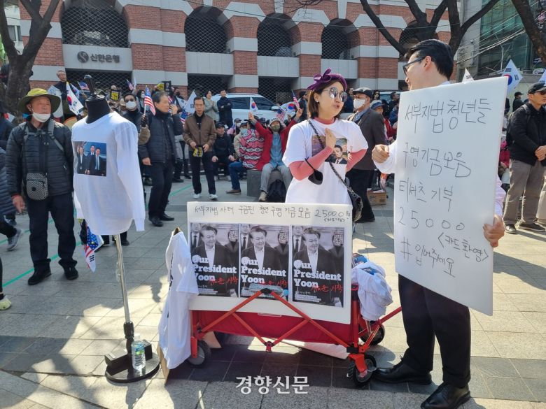 한 노점상이 22일 서울 종로구 윤석열 대통령 탄핵 반대 집회 한쪽에서 윤 대통령 티셔츠를 판매하고 있다. 서현희 기자