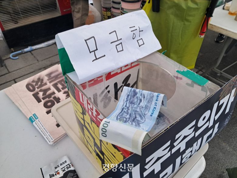 청소노동자 박종임씨(77)가 5일 비상행동의 진행 부스에 있는 모금함에 천원짜리 한장을 올려두었다.  모금된 돈은 집회의 운영비로 사용된다. 박정연 기자