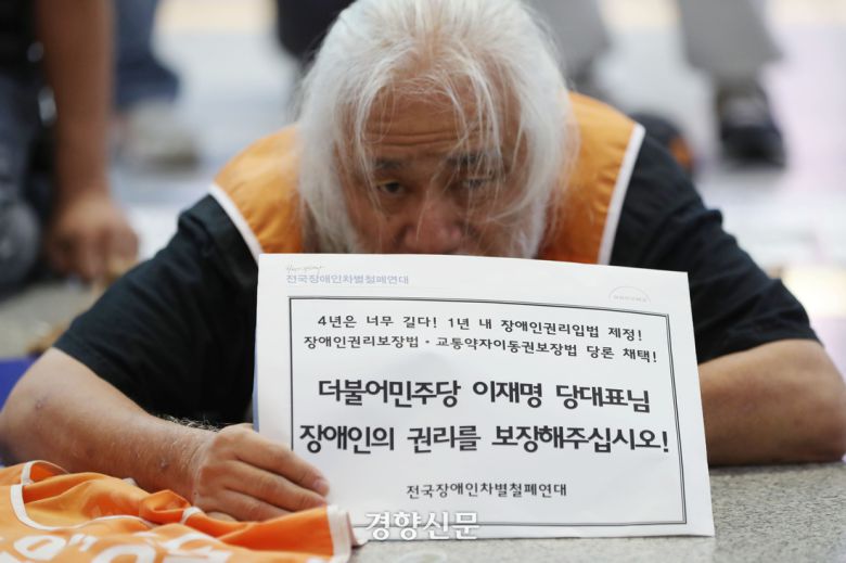 박경석 전국장애인차별철폐 연대 공동 대표가 지난 9월 서울 용산역에서 시민들에게 귀성길 인사를 하는 이재명 더불어민주당 대표에게 장애인 이동·교육·노동 등 7대 권리입법 통과를 요청하기 위한 포체투지를 하고 있다. 한수빈 기자