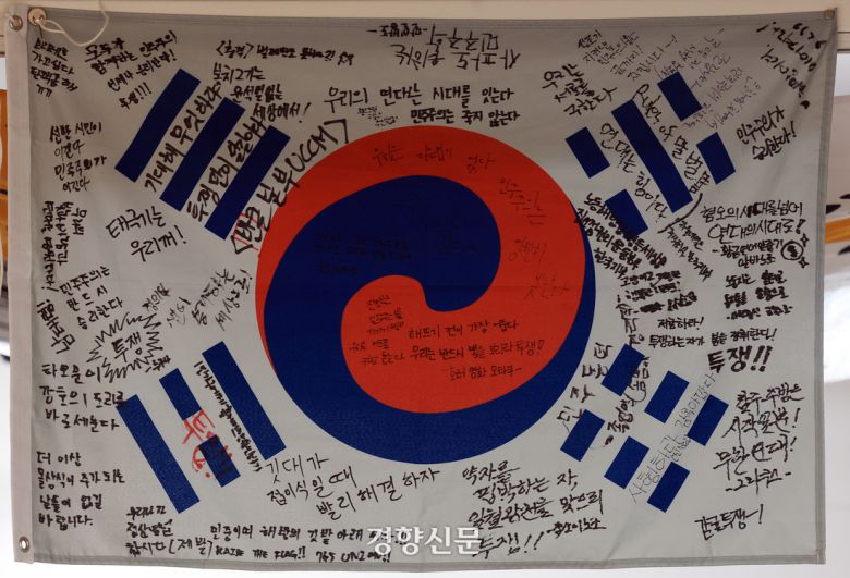 <민주주의와 깃발> 개막을 이틀 앞둔 14일 서울 용산구 식민지역사박물관  전시장 천장에  ‘윤석열 탄핵’ 집회 현장에서 사용된 깃발이 매달려 있다. 서성일 선임기자