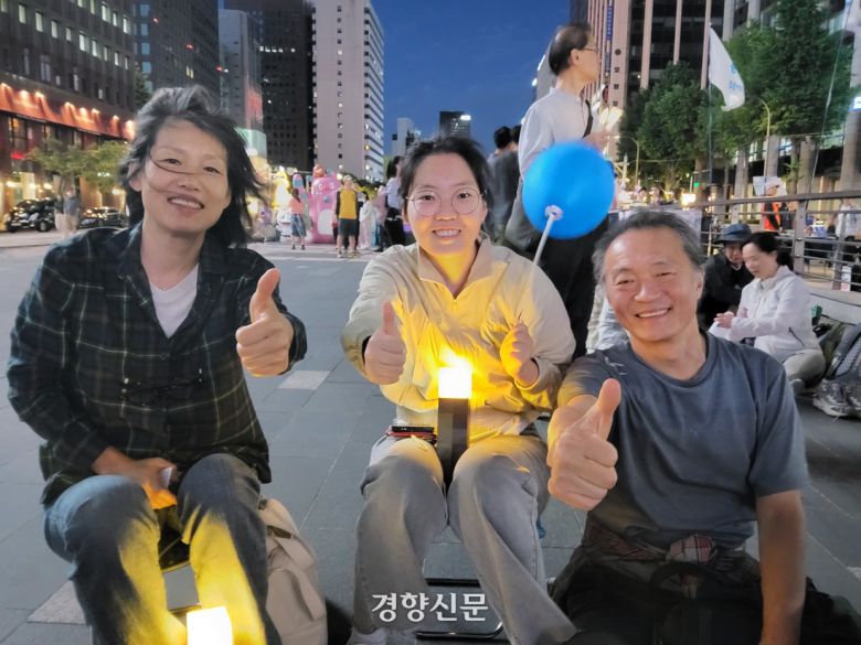 이미선(59·왼쪽부터)·위한슬(30)·위성계씨(61) 가족이 3일 서울 중구 청계과장에서 촛불행동 등이 주최한 개표방송 집회에 참가해 포즈를 취하고 있다. 김태욱 기자