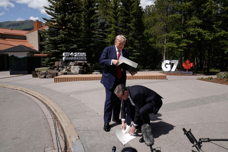 키어 스타머 영국 총리(오른쪽)가 16일(현지시간) 도널드 트럼프 미국 대통령이 떨어뜨린 미·영 무역협정 서류를 줍고 있다. AP연합뉴스