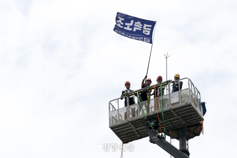 김형수 금속노조 거제통영고성조선하청지회장이 19일 고공농성을 벌이던 철탑에서 내려오며 금속노조 깃발을 흔들고 있다. 문재원 기자