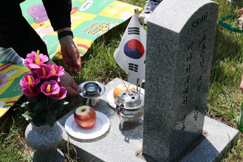 6·25전쟁 75주년을 사흘 앞둔 22일 서울 동작구 국립서울현충원 묘역에서 유족 홍인표씨가 가족들과 함께 아버지 묘지를 찾아 참배하고 있다. 성동훈 기자