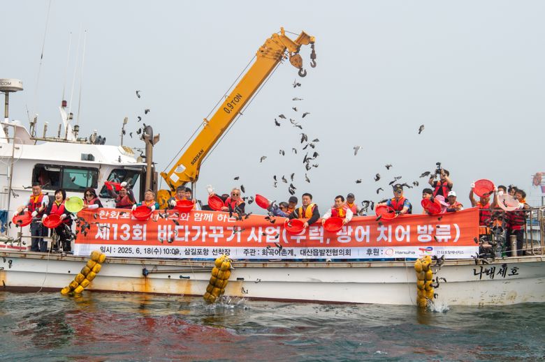 한화토탈에너지스 임직원과 지역주민들이 서산시 대산읍 삼길포에서 치어를 방류하고 있다. 한화토탈에너지스 제공