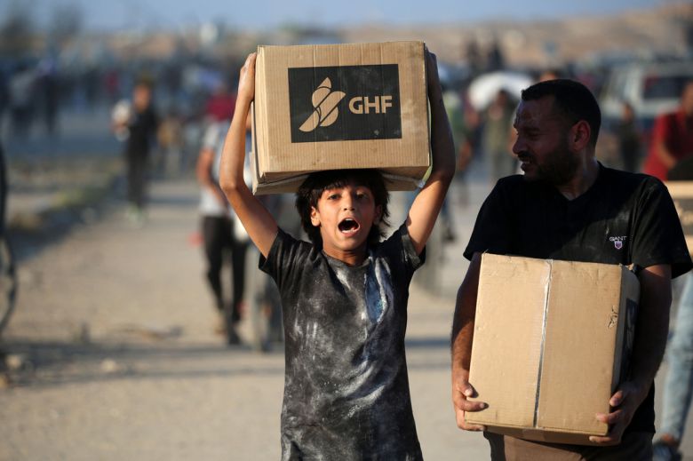 25일(현재시간) 식량을 구하는 팔레스타인 사람들이 가자지구 세이라트 난민 캠프 근처의 살라 알딘 도로를 따라 가자인도주의재단(GHF)이 설치한 구호품 배급소에 도착하기 위해 걸어가고 있다. AFP연합뉴스