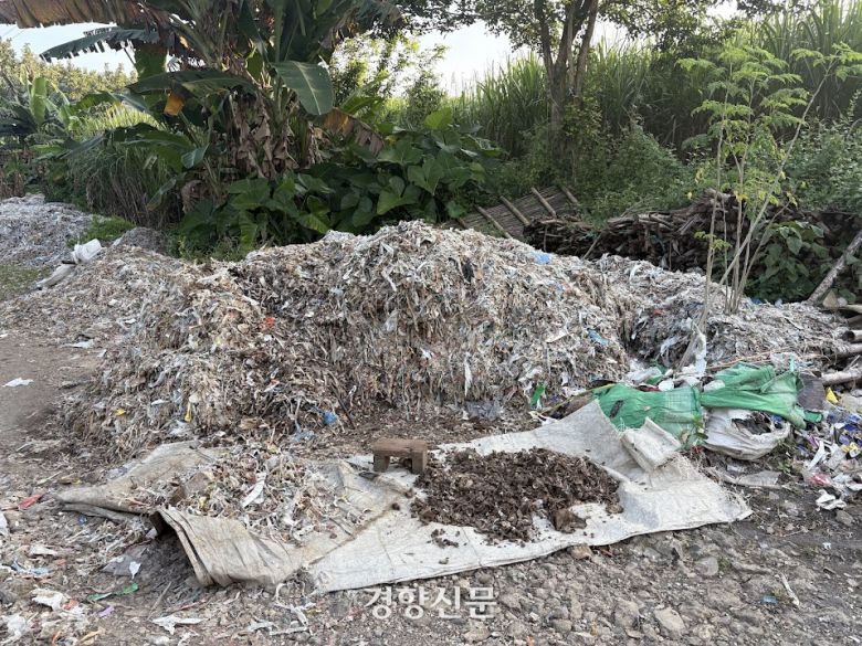 감핑안 마을 귀퉁이에 플라스틱과 종이 쓰레기 조각이 뒤섞인 채 쌓여있다. 마을 주민들은 쓰레기 더미에서 맨손으로 종잇조각을 골라내 인근 제지 공장에 판다. 주민이 골라낸 종잇조각이 쓰레기 더미 앞에 놓여 있다. 오경민 기자