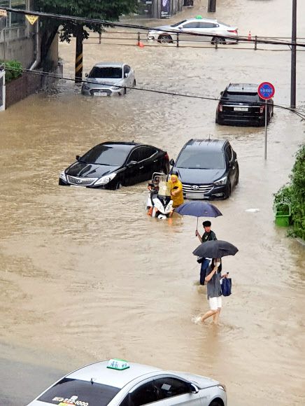 차도, 사람도 힘겹게 - 7일 오후 광주에 폭우가 내린 가운데 광주 북구 중흥동 도로에 한때 물이 차 차와 오토바이, 행인들이 조심스럽게 서행하고 있다. 2020. 8. 7 광주 북구 제공