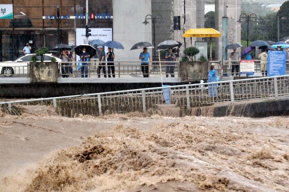 범람 위기 광주천 지켜보는 시민들 - 폭우가 내린 7일 오후 광주 서구 양동복개상가 앞 광주천에서 시민들이 거센 급류를 지켜보고 있다. 2020.8.7 연합뉴스