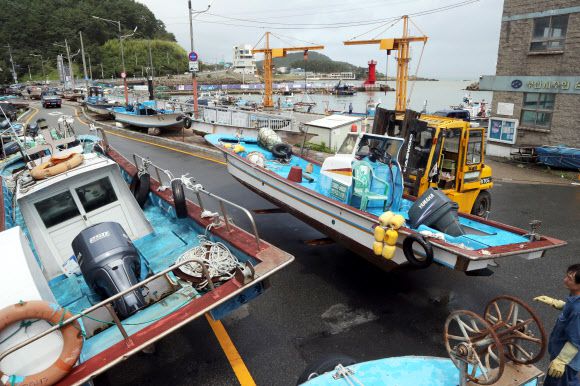 제5호 태풍 ‘장미’가 한반도를 향해 북상 중인 9일 부산 해운대구 송정어촌계 어민들이 중장비를 이용해 어선을 도로 위로 옮기고 있다. 2020.8.9 연합뉴스