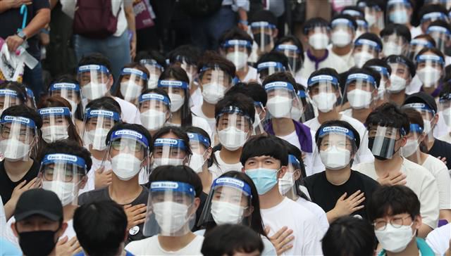 집단휴진 총파업에 나선 대한의사협회 회원들이 14일 오후 서울 영등포구 여의대로에서 열린 ‘4대 악(惡) 의료 정책 저지를 위한 전국의사총파업 궐기대회’에서 페이스쉴드를 착용한 채 국민의례를 하고 있다. 2020.8.14 뉴스1