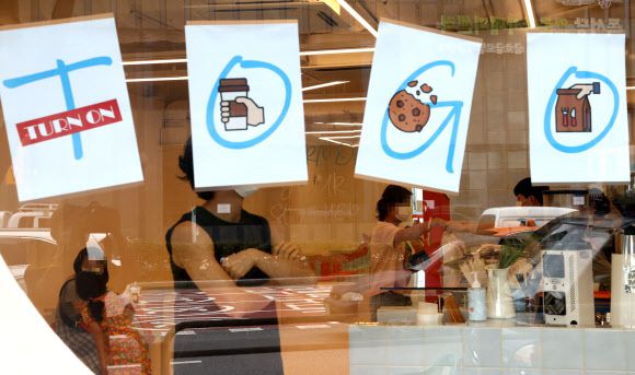 포장이 대세 - 수도권에 사회적 거리두기 2.5단계가 시행된 지 이틀째인 31일 서울 성동구의 한 개인 카페 유리벽에 주문한 음식을 포장해 갈 것을 손님들에게 알리는 표지가 붙어 있다. 프랜차이즈형 커피전문점이 아닌 카페는 낮시간 정상 영업도 가능하다.연합뉴스