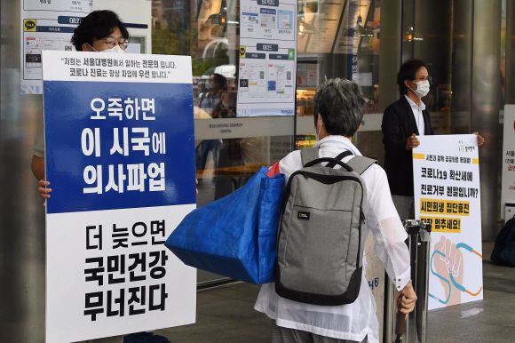 - 2일 서울대병원 본관 앞에서 왼쪽엔 한 전공의가 정부의 의료정책을 반대하는 내용이 적힌 피켓을 들고 있고 오른쪽엔 윤홍식 참여연대 사회복지위원장이 의사협회의 진료거부 철회를 촉구하는 1인 시위를 하고 있다. 2020.9.2 오장환 기자 5zzang@seoul.co.kr