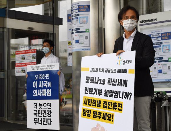 파업에 참여한 서울대병원 소속 전문의(왼쪽)가 2일 서울 종로구 서울대병원 본관 앞에서 정부가 추진하는 의료정책에 반대하는 내용의 피켓을 들고 있다. 그 오른쪽에선 윤홍식 참여연대 사회복지위원장이 집단행동에 나선 의사들을 비판하는 내용의 피켓을 들고 1인 시위를 하고 있다. 오장환 기자 5zzang@seoul.co.kr