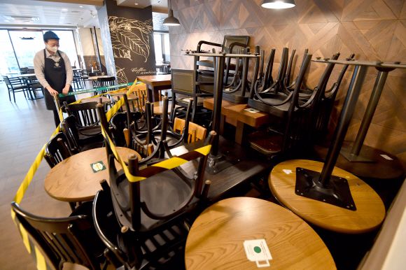 코로나19 확산을 막기 위한 사회적 거리두기 2단계 시행을 하루 앞둔 23일 서울의 한 프랜차이즈 커피 매장에서 직원이 테이블을 정리하고 있다. 박지환 기자 popocar@seoul.co.kr