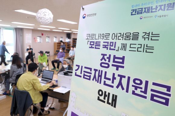 또 받을 수 있을까?  - 코로나19 3차 유행으로 사회적 거리두기가 강화되면서 정치권을 중심으로 3차 재난지원금 지급이 논의되고 있다. 사진은 지난 5월 1차 재난지원금 지급 때 현장 접수를 시작한 서울 성동구 금호2-3가동주민센터 모습.서울신문 DB