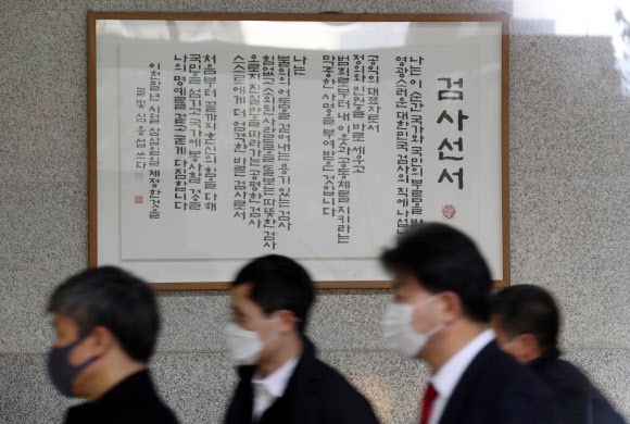 ‘검사선서’ 앞 지나는 중앙지검 관계자들 - 윤석열 검찰총장의 직무배제에 반발하는 평검사 회의가 26일 동시다발적으로 진행될 것으로 보인다.     법조계에 따르면 서울중앙지검 내 36기 수석 평검사들은 이날 회의를 열어 전체 평검사 회의 방안을 논의한다. 이들은 회의에서는 지검 내 전체 평검사 회의 개최 여부와 의견 표현 방식 등을 결정할 것으로 보인다.      사진은 26일 서울 서초구 서울중앙지검에서 점심을 먹기 위해 청사를 나서는 검찰 관계자들. 2020.11.26 연합뉴스