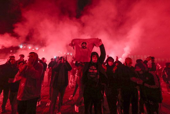 이탈리아 프로축구 나폴리의 황금기를 일군 디에고 마라도나를 추모하기 위해 26일(현지시간) 나폴리 도심 피아차 플레비치토스에 모인 팬들이 고인 사진이 들어간 상의 등을 들어 보이며 홍염을 태우고 있다.나폴리 AP 연합뉴스