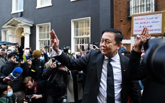 런쪼 츠와 민 전 영국 주재 미얀마 대사가 전날(이하 현지시간) 저녁부터 대사관 출입이 봉쇄돼 건물 앞 승용차 안에서 밤들 지낸 뒤 8일 아침 몰려온 지지자들과 함께 군부에 저항을 상징하는 세 손가락 경례를 하고 있다.런던 EPA 연합뉴스