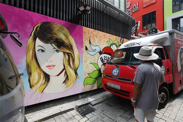 29일 서울 종로구의 한 서점 벽면에 그려진 윤석열 전 검찰총장의 배우자 김건희 씨를 비방하는 내용의 벽화를 보수단체 관계자들이 차량으로 막아서고 있다.앞서 지난달 김건희씨는 자신이 ‘강남 유흥주점의 접객원 쥴리였다’는 루머에 대해 “누가 소설을 쓴 것”이라고 해명했다.윤석열 대선 예비후보 캠프는 지난 27일 김건희에 대한 루머가 확산되고 있는 것에 강력히 대응하겠다고 밝혔다. 2021.7.29뉴스1