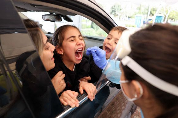 이스라엘 예루살렘의 한 어린이가 11일(현지시간) 코로나19 드라이브스루 검사소에서 가족들이 탄 차 안에서 바이러스 검사를 받고 있다.예루살렘 AFP 연합뉴스