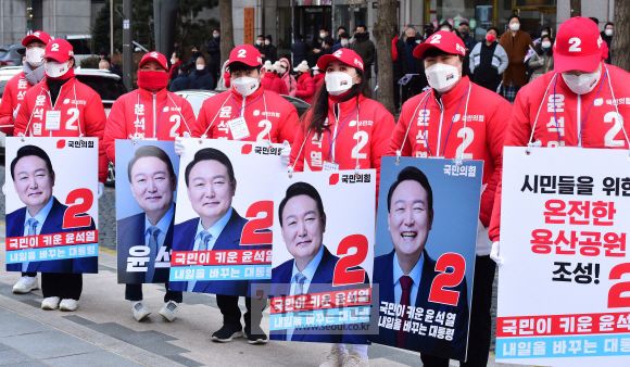 국민이 키운 윤석열 - 빨간색 점퍼를 입은 윤석열 국민의힘 대선후보 선거운동원들이 15일 서울 청계광장에서 ‘국민이 키운 윤석열, 내일을 바꾸는 대통령’ 피켓을 목에 메고 선거운동을 하고 있는 모습.서울 오장환 기자