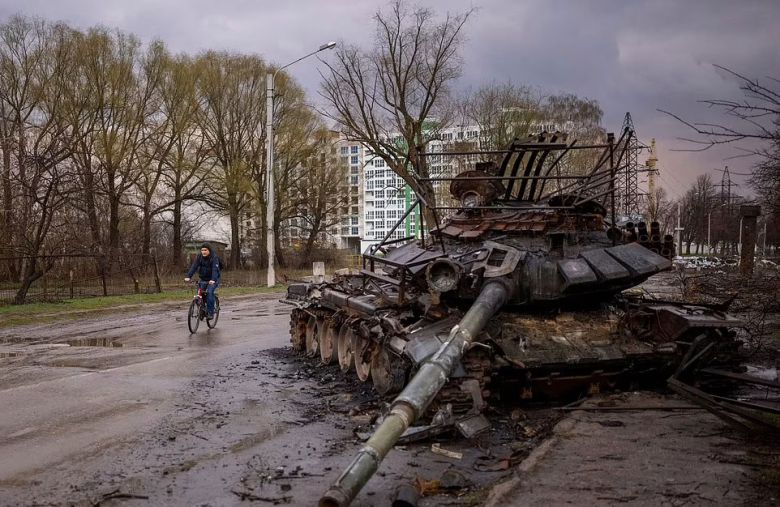 우크라이나 체르니히우에서 지난 21일(현지시간) 자전거를 탄 한 주민이 러시아군의 파괴된 전차 옆을 지나가고 있다. AP 연합뉴스