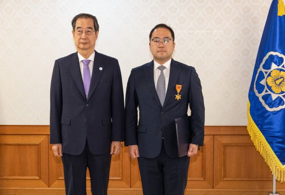 한덕수(왼쪽) 국무총리가 24일  정부서울청사에서 열린 정부 업무평가 유공자 포상 수여식에서 박진홍 국토교통부 과장에게 녹조 근정훈장을 수여한 뒤 기념촬영을 하고 있다. 연합뉴스