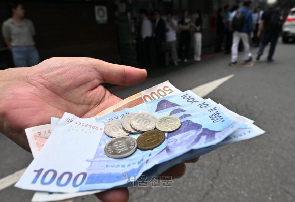 내년 시간당 최저임금이 올해 9620원에서 2.5%(240원) 인상된 9860원으로 결정됐다. 주휴수당을 감안한 월급으로는 206만 740원이다. 사진은 23일 서울 식당가를 찾은 한 시민이 내년 최저시급인 9860원을 손에 든 모습. 홍윤기 기자